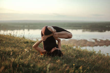 Yoga practice and meditation in nature in sunrise. Woman practicing near big river Kamaの写真素材