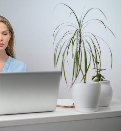 A girl with a laptop is studying at an online school. White room background
