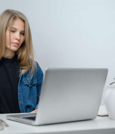 A girl with a laptop is studying at an online school. White room backgroundの写真素材