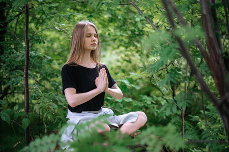 Practice of meditation and interaction with nature. Girl in green forest