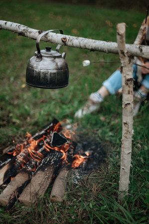 Campfire near the trailer home.Couple in a checkered plaid roasting marshmallows