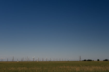 Wind Turbines Windmill Energy Farm on green field and blue sky
