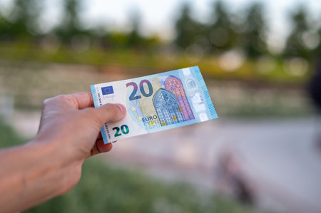 First person top view photo of hands holding fan of Euro banknotes on park backgroundの写真素材