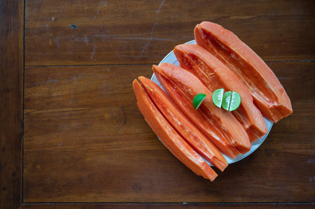 Sliced papaya with lime on table near swimming poolの写真素材
