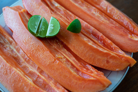 Sliced papaya with lime on table near swimming poolの写真素材