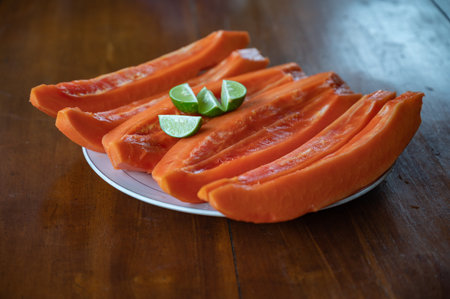 Sliced papaya with lime on table near swimming poolの写真素材