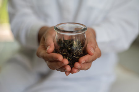 Woman in white clothes with mock up jar with green tea in handsの写真素材