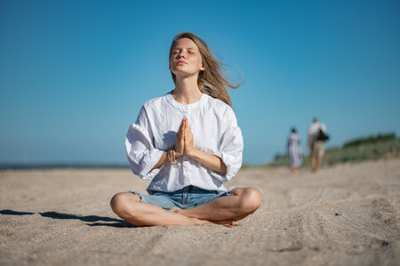 Girl practice meditation on the beach. With space for text or designの写真素材