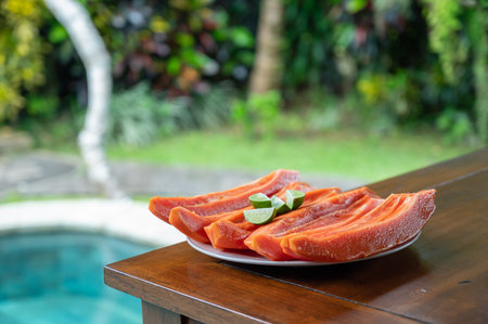 Sliced papaya with lime on table near swimming poolの写真素材