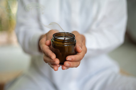 Woman in white clothes with mock up candle in jar in handsの写真素材