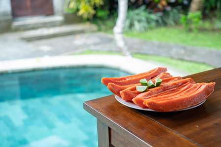 Sliced papaya with lime on table near swimming poolの写真素材