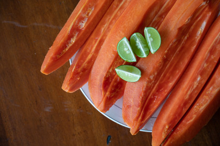 Sliced papaya with lime on table near swimming poolの写真素材