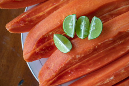 Sliced papaya with lime on table near swimming poolの写真素材