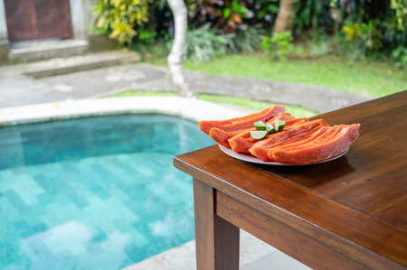Sliced papaya with lime on table near swimming poolの写真素材