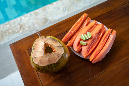 Sliced papaya with lime on table near swimming poolの写真素材