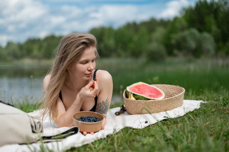 Girl relaxing and eat watermelon outdoor near lake. Picnic in natureの写真素材