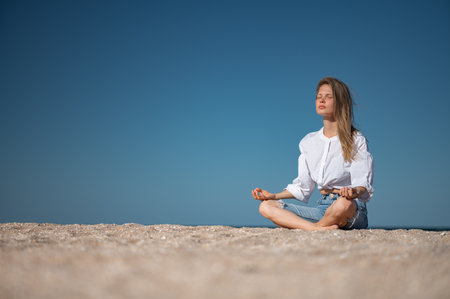 Girl practice meditation on the beach. With space for text or designの写真素材