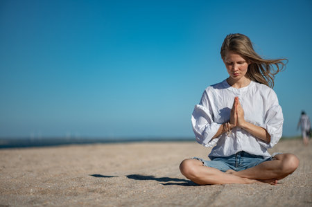 Girl practice meditation on the beach. With space for text or designの写真素材