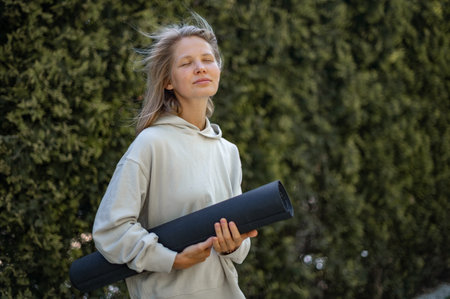 Girl with yoga mat in hand outdoorの写真素材