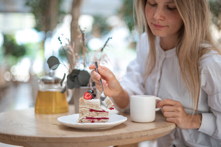Attractive girl drinking tea with cake in cafeの写真素材
