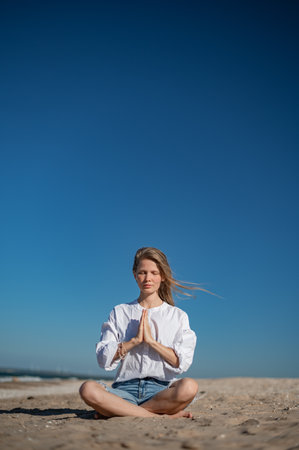 Girl practice meditation on the beach. With space for text or designの写真素材