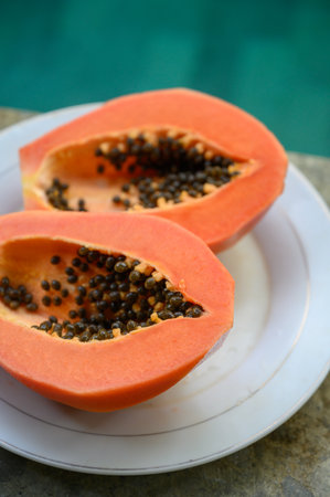 Two halves of peeled papaya in plate near swimming poolの写真素材