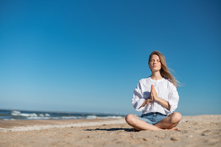 Girl meditating by the sea. Wind shakes long blond hairの写真素材