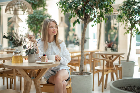 Attractive girl drinking tea with cake in cafeの写真素材