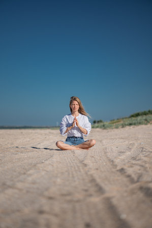 Girl meditating by the sea. Wind shakes long blond hairの写真素材