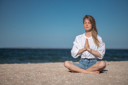 Girl meditating by the sea. Wind shakes long blond hairの写真素材