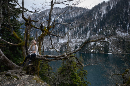 Girl sits on a tree and meditates near lake Ritsa in Abkhaziaの写真素材