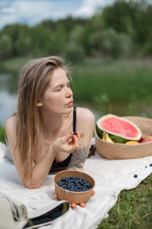 Girl relaxing and eat watermelon outdoor near lake. Picnic in natureの写真素材