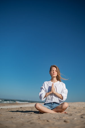 Girl practice meditation on the beach. With space for text or designの写真素材
