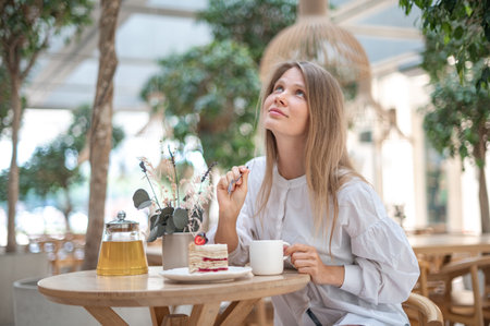 Attractive girl drinking tea with cake in cafeの写真素材