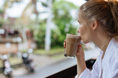 Girl drinking coffee and looking outsideの写真素材
