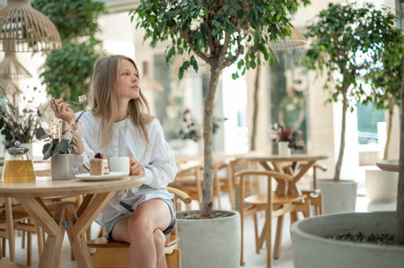 Attractive girl drinking tea with cake in cafeの写真素材