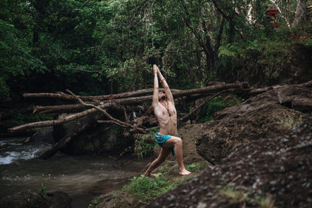Yoga practice and meditation in nature. Man practicing near riverの写真素材