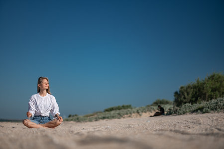 Girl practicing meditation on the beach.の写真素材