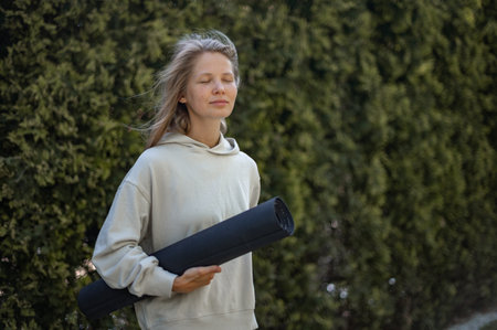Girl with yoga mat in hand outdoorの写真素材