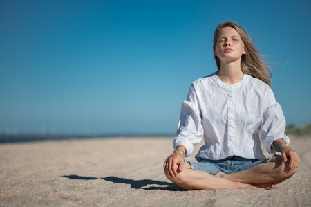 Girl practice meditation on the beach. With space for text or designの写真素材