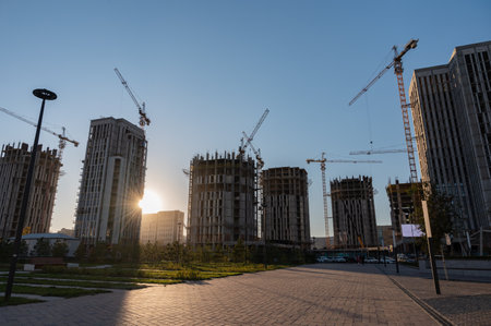 Tall buildings under construction and cranes under a blue skyの写真素材