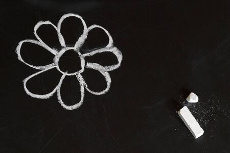 White flower on a blackboard, child chalk drawing stylizationの写真素材