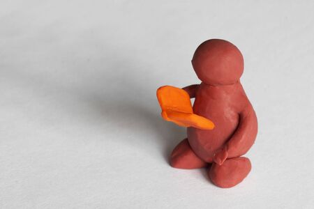 Plasticine man reading the book over grey backgroundの写真素材