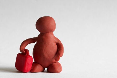 Plasticine man with a red suitcase over grey backgroundの写真素材