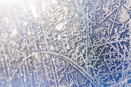 Extreme close-up shot of frozen window with beautiful natural ice ornament (partial blurred)