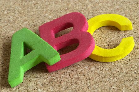 3D Plastic ABC letters over cork desk background macro shotの写真素材