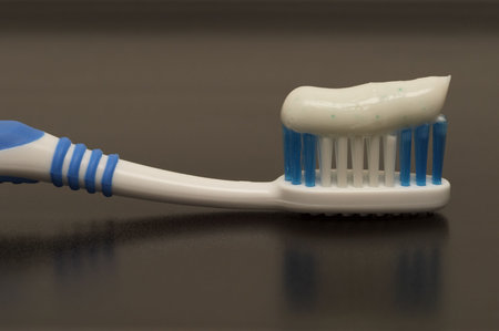 Toothbrush fragment on the black surface with a toothpaste macro shot