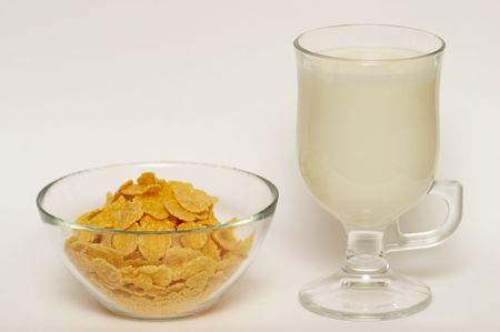 Cornflakes and milk in the bowl and glass isolated over white background (shallow depth of field)の写真素材