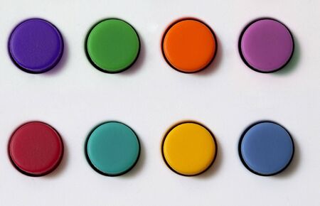 Colored plastic buttons set over white textured backgroundの写真素材