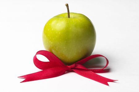 Green apple and red ribbon bow isolated over white backgroundの写真素材